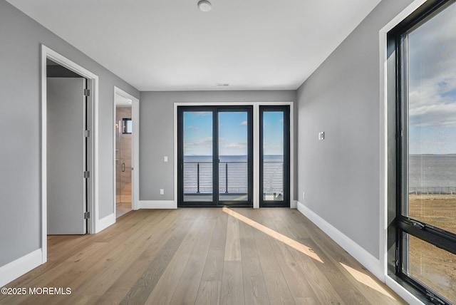 spare room with light hardwood / wood-style flooring and a water view