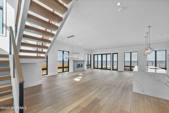 unfurnished living room featuring plenty of natural light, sink, and light wood-type flooring