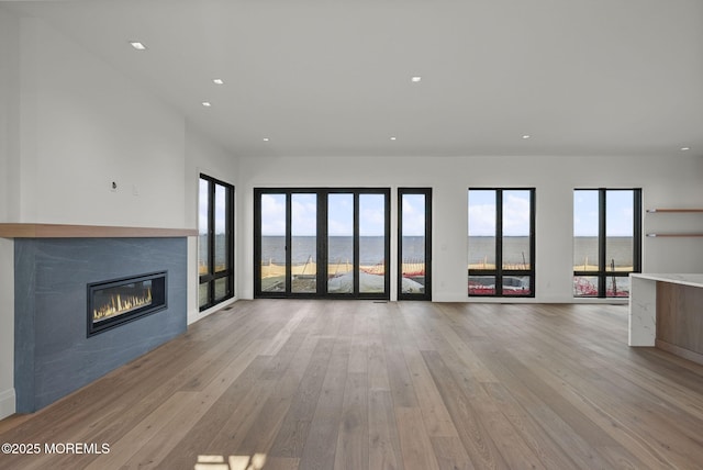 unfurnished living room featuring light hardwood / wood-style floors and a water view