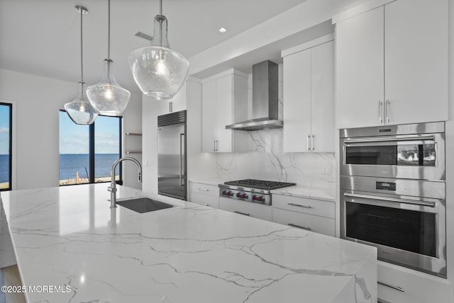 kitchen with stainless steel appliances, a water view, light stone counters, and wall chimney exhaust hood