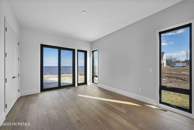 spare room with hardwood / wood-style floors and a water view