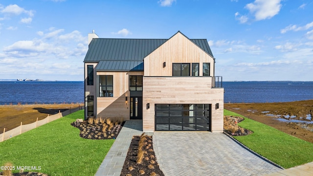 view of front of home featuring a garage, a front lawn, and a water view