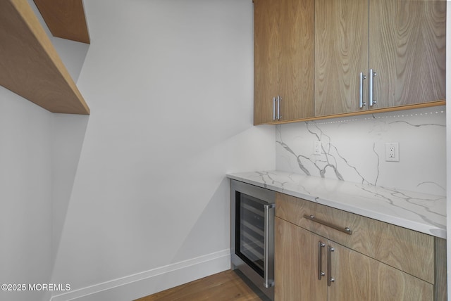 bar featuring beverage cooler, light stone countertops, hardwood / wood-style floors, and decorative backsplash