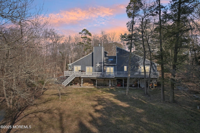 back of property with a chimney, stairway, a deck, and a lawn