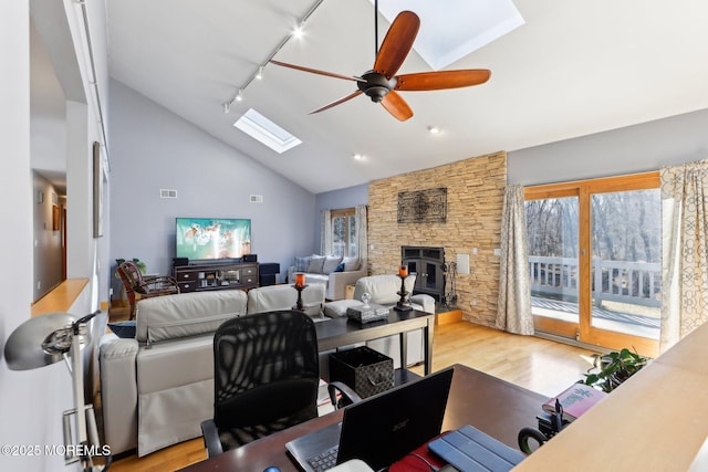 living room with a skylight, light wood-style floors, ceiling fan, track lighting, and high vaulted ceiling