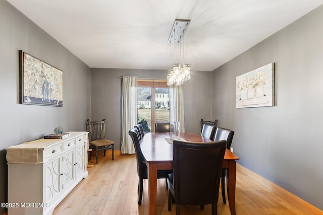 dining area with light wood-style flooring and a notable chandelier