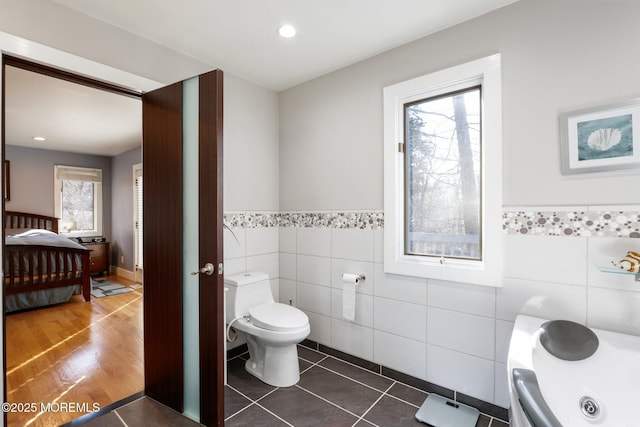 bathroom featuring tile walls, recessed lighting, toilet, wainscoting, and tile patterned floors