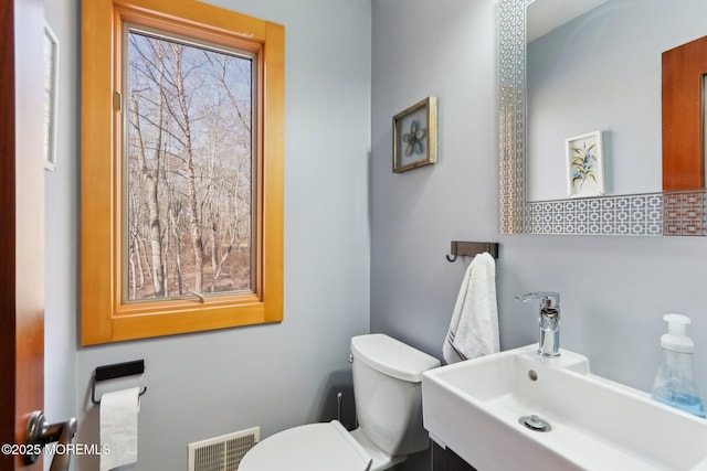 bathroom featuring toilet, visible vents, and a sink