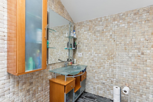 bathroom with vaulted ceiling, tile walls, and vanity