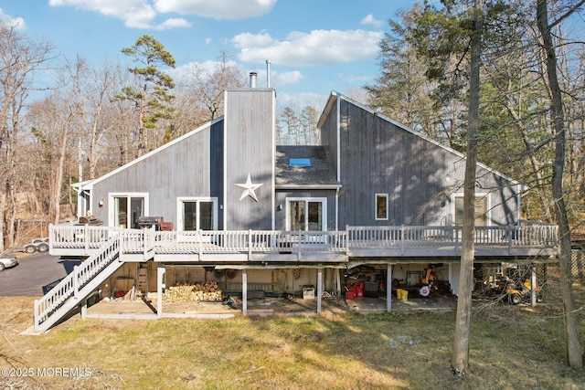 rear view of property featuring stairs, a chimney, a lawn, and a wooden deck