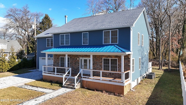 view of front of property with a porch, a garage, cooling unit, and a front yard