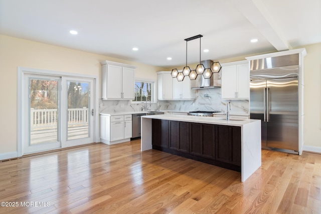 kitchen featuring pendant lighting, stainless steel appliances, a center island, tasteful backsplash, and white cabinets