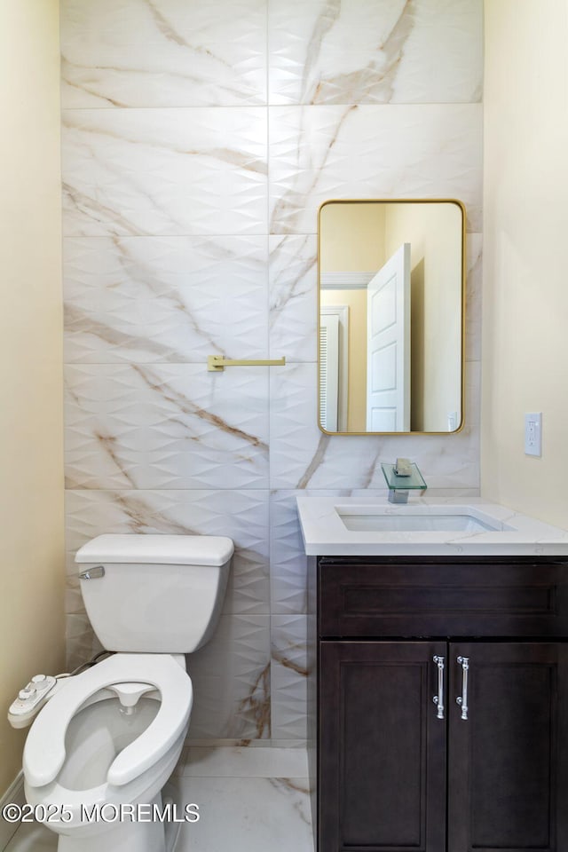 bathroom with vanity, tile walls, and toilet