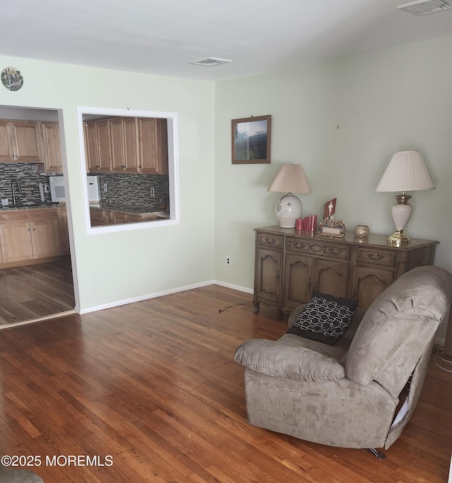 living area featuring sink and dark wood-type flooring