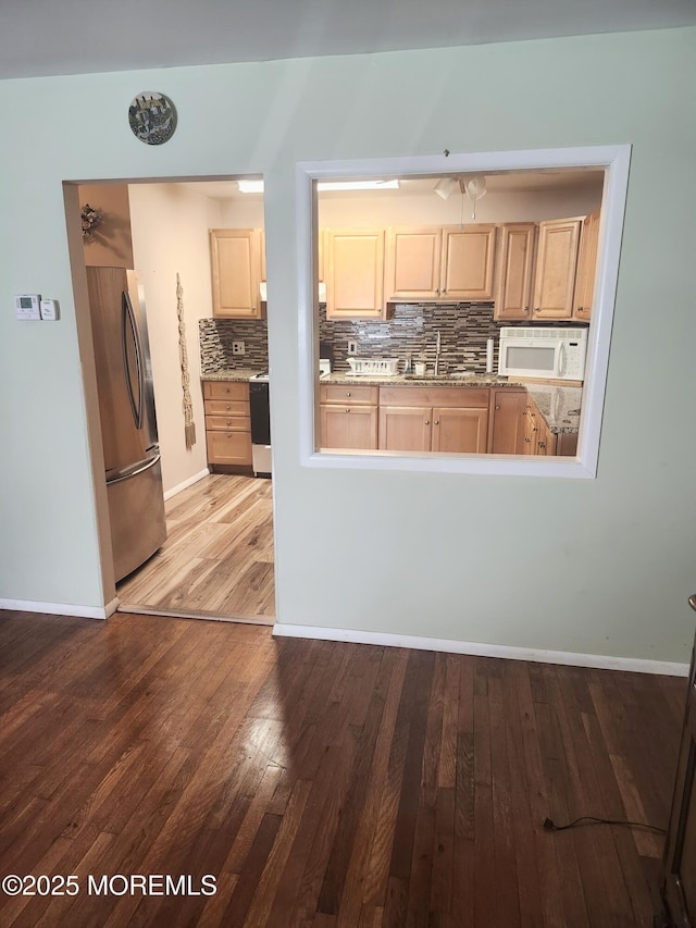 kitchen with tasteful backsplash, light brown cabinets, stainless steel refrigerator, hardwood / wood-style floors, and sink