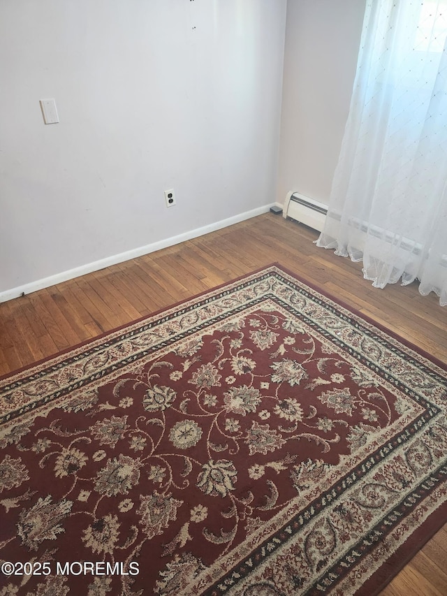 empty room with baseboard heating and wood-type flooring