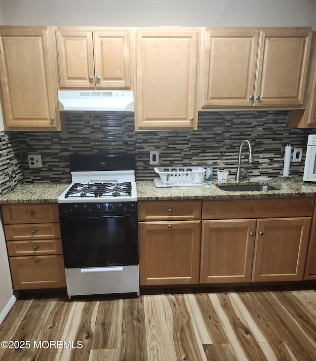 kitchen with light stone countertops, sink, backsplash, and black gas stove