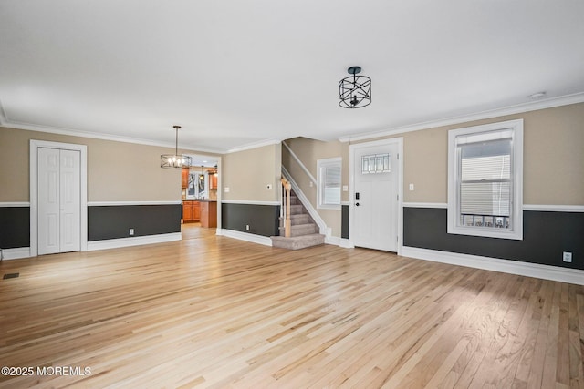 unfurnished living room with ornamental molding, a chandelier, and light hardwood / wood-style flooring