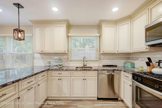 kitchen featuring dark stone counters, tasteful backsplash, appliances with stainless steel finishes, and a sink