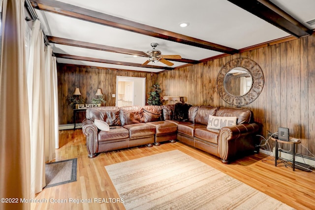 living room with wooden walls, wood finished floors, a ceiling fan, beam ceiling, and baseboard heating