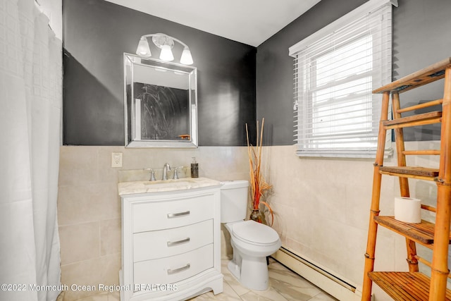 bathroom featuring vanity, wainscoting, a baseboard heating unit, tile walls, and toilet