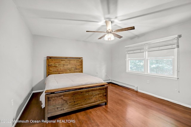 bedroom with ceiling fan, a baseboard heating unit, baseboards, and wood finished floors