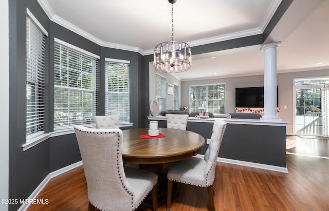 dining space featuring ornamental molding, wood-type flooring, plenty of natural light, and ornate columns