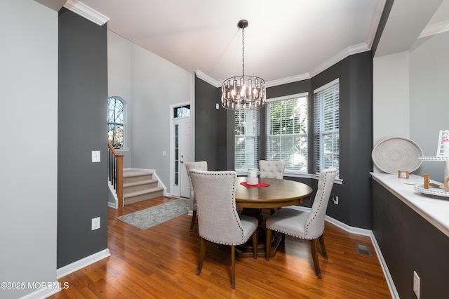 dining area featuring crown molding, a healthy amount of sunlight, a chandelier, and hardwood / wood-style floors