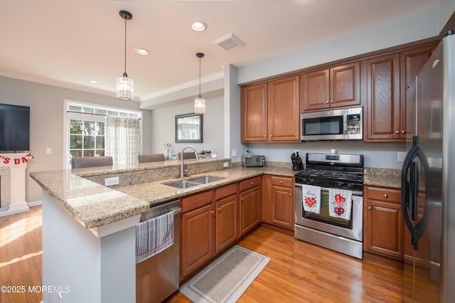 kitchen featuring sink, light stone counters, appliances with stainless steel finishes, kitchen peninsula, and light hardwood / wood-style floors