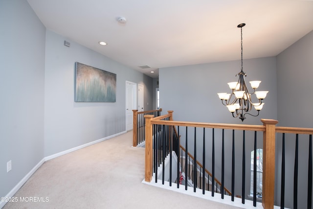 hallway with an inviting chandelier and light carpet