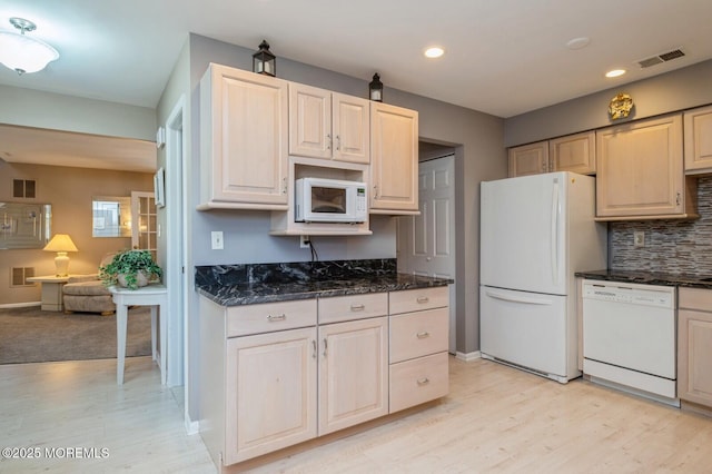 kitchen with backsplash, white appliances, light hardwood / wood-style floors, and dark stone countertops