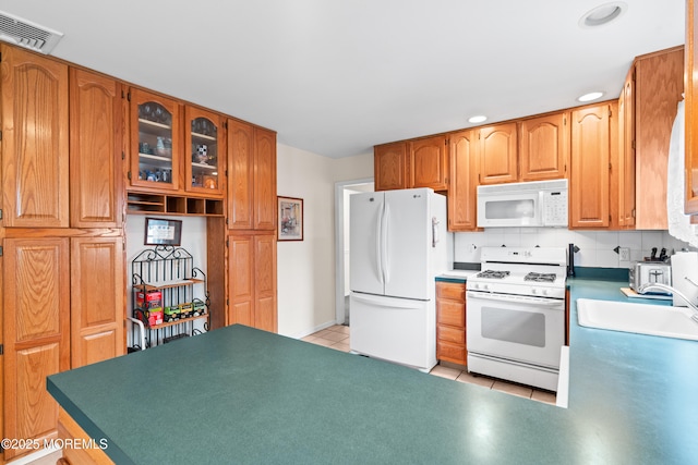 kitchen with white appliances, light tile patterned floors, visible vents, a sink, and backsplash