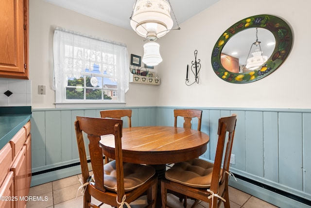 dining room with light tile patterned floors, wainscoting, and a baseboard radiator