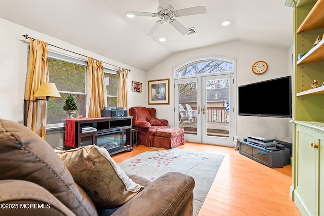 living area with french doors, visible vents, light wood-style floors, vaulted ceiling, and ceiling fan