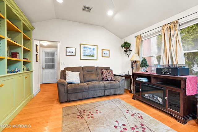 living room with lofted ceiling, visible vents, and light wood-style flooring