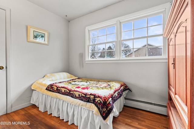 bedroom with a baseboard heating unit, baseboards, and wood finished floors