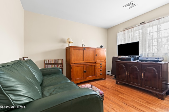 living room with visible vents, light wood-style flooring, and baseboard heating