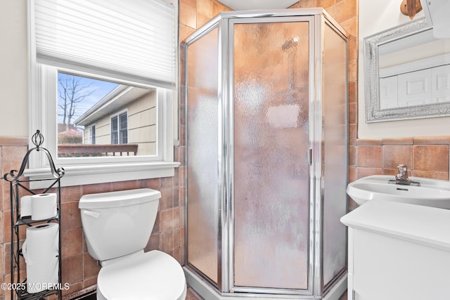 full bathroom featuring toilet, a sink, tile walls, wainscoting, and a shower stall