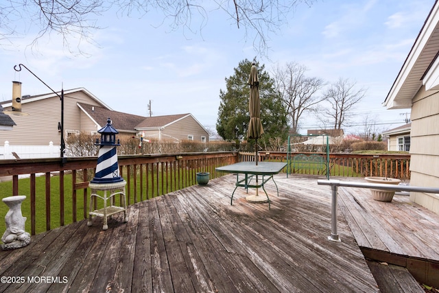 wooden deck with a yard, a trampoline, and fence