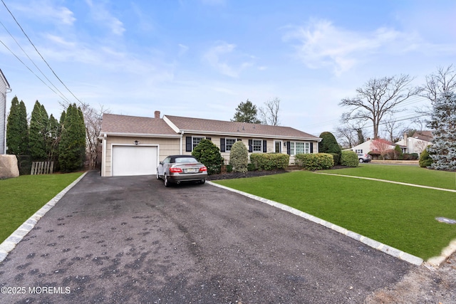 view of front of home with aphalt driveway, a chimney, a shingled roof, an attached garage, and a front lawn