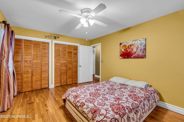 bedroom featuring ceiling fan, multiple closets, and light wood-type flooring