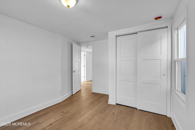 unfurnished bedroom featuring light wood-type flooring and a closet