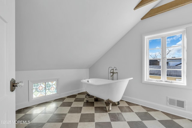 bathroom featuring a healthy amount of sunlight, a tub to relax in, and vaulted ceiling