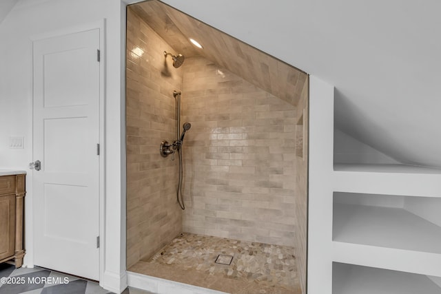 bathroom with vanity, lofted ceiling, and tiled shower