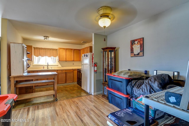 kitchen with sink, light hardwood / wood-style floors, black range with electric stovetop, and white fridge