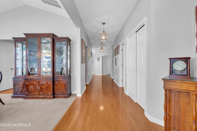 hall with vaulted ceiling and light colored carpet