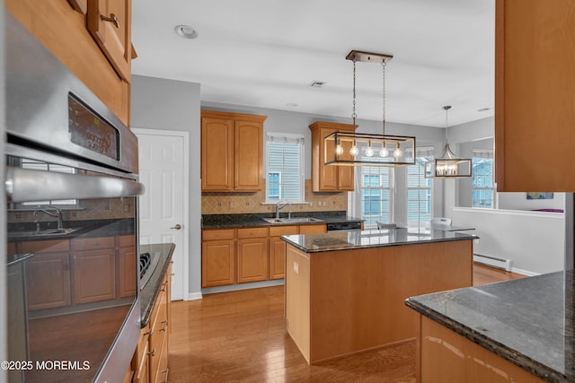 kitchen featuring a center island, pendant lighting, dark stone counters, a baseboard heating unit, and tasteful backsplash