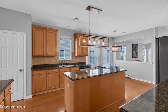 kitchen featuring light wood-type flooring, a center island, sink, appliances with stainless steel finishes, and pendant lighting