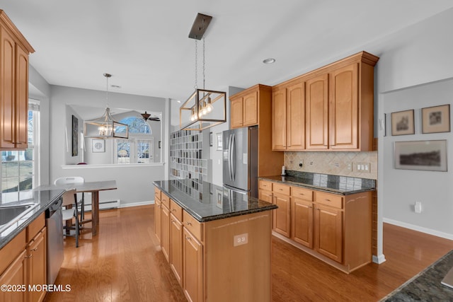 kitchen featuring light hardwood / wood-style flooring, a center island, stainless steel appliances, hanging light fixtures, and tasteful backsplash