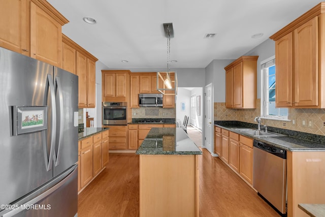 kitchen with sink, a center island, light hardwood / wood-style floors, stainless steel appliances, and hanging light fixtures